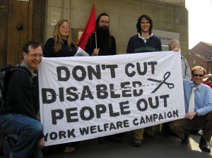 Campaigners with a banner reading "Don't Cut Disabled People Out"